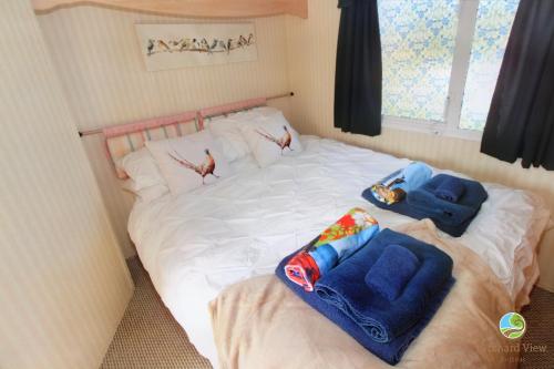 a bed with two pillows and two birds on it at Orchard View Retreat - Dog friendly, enclosed private garden with weather dependant hot tub - Not on a holiday park in Little Clacton