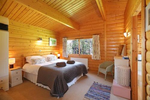a bedroom with a bed in a log cabin at Birchlea in Kippford