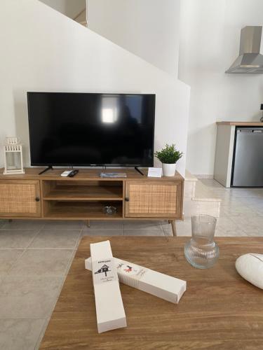 a living room with a flat screen tv and a table at Olea White in Skiathos Town