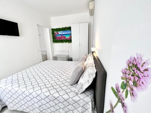 a white bedroom with a bed and flowers on the wall at Innsud in Nardò