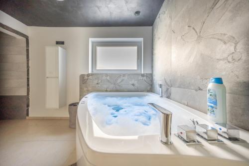 a bathroom with a bathtub with a blue bathruct at Resort TimAJA - pool, massage pool, sauna in Trebnje