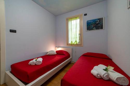 een slaapkamer met 2 bedden met rode lakens en een raam bij ISEO SMILE house in Iseo