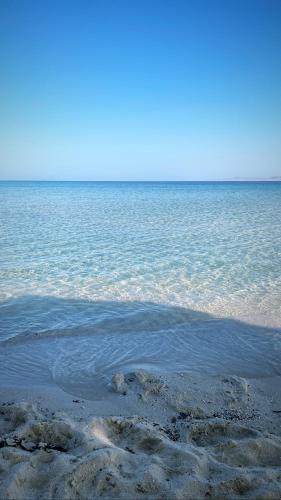 a large body of water with rocks in the sand at La Casa Guest House in Marsa Alam City