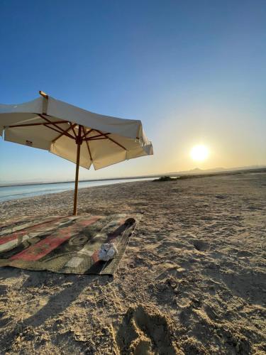 a beach with an umbrella and a towel on the sand at La Casa Guest House in Marsa Alam City