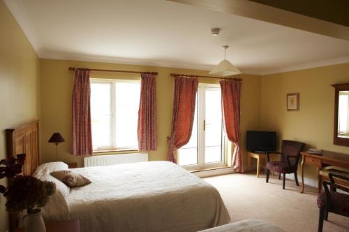 a bedroom with a bed and a desk and two windows at Seapoint House in Westport