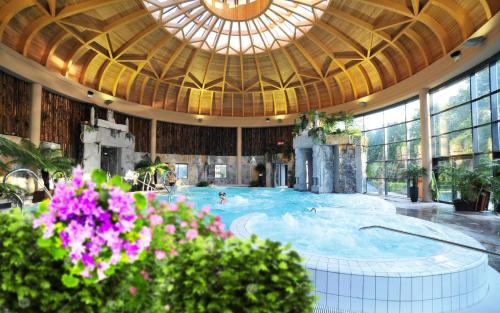 - une piscine avec des personnes dans un grand bâtiment dans l'établissement Le Balcon du Parc, entre Lourdes et Gavarnie, à Argelès-Gazost