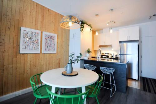 a kitchen and dining room with a white table and green chairs at La Réserve du Boisé - Parking, terrasse & Gym in Quebec City