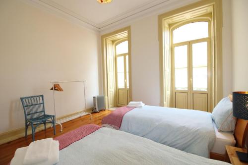 a bedroom with two beds and a chair and a window at Casa 11 Cravos in Figueira da Foz