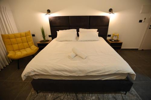 ein Schlafzimmer mit einem großen weißen Bett und einem gelben Stuhl in der Unterkunft Puy Castele Hotel Tiberias in Tiberias