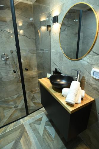 ein Bad mit einem Waschbecken und einer Dusche mit einem Spiegel in der Unterkunft Puy Castele Hotel Tiberias in Tiberias