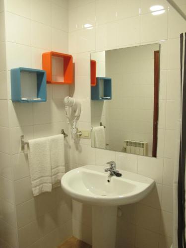 a bathroom with a sink and a mirror and towels at Apartamentos Turísticos Cancelas by Bossh Hotels in Santiago de Compostela