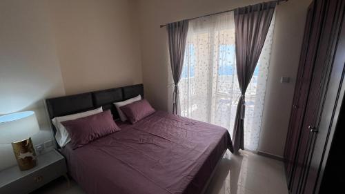 a bedroom with a bed with purple sheets and a window at Stunning high floor Ocean front Retreat with Panoramic Sea Views for Rent in Ras al Khaimah
