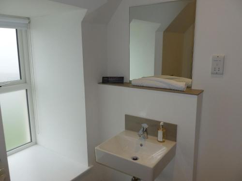 een witte badkamer met een wastafel en een spiegel bij Buckie - 1 Bedroom with ensuite in Wick