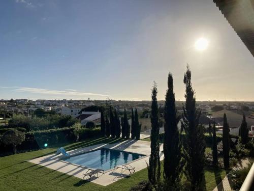 a swimming pool in a yard with cypress trees at Panorama Apartment Sagres *Pool* in Sagres