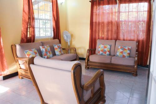 a living room with two chairs and a couch at Buttercup Cottage Apartments in Arnos Vale