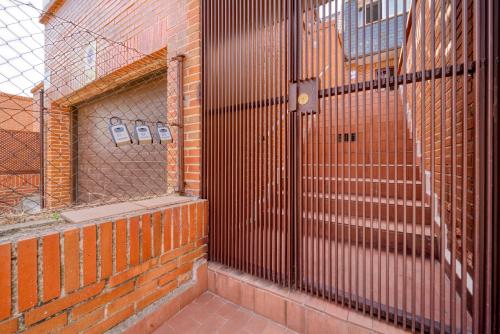 a brick wall with a gate on the side of a building at A CASACAFÉ Madrid Pozuelo Estación Private Rooms in Pozuelo de Alarcón