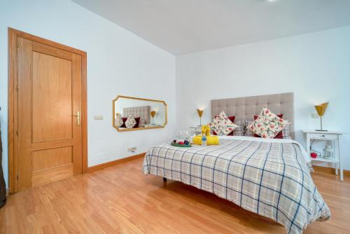 a bedroom with a bed with a checked blanket and a mirror at A CASACAFÉ Madrid Pozuelo Estación Private Rooms in Pozuelo de Alarcón