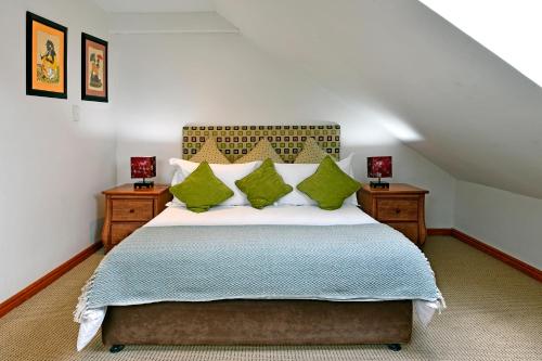 a bedroom with a large bed with green pillows at The Coach House in Franschhoek
