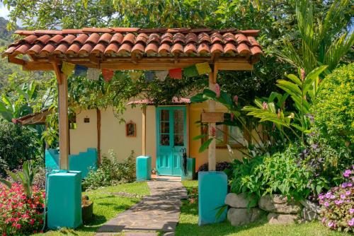 a small house with a blue door and a red roof at Rio Chirripo in Rivas