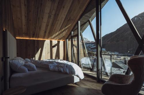 um quarto com uma cama e uma grande janela em Amus Chalets Dolomites - Luxury Chalets South Tyrol em Anterselva di Mezzo