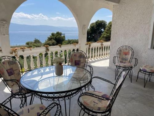 - une table et des chaises en verre sur une terrasse donnant sur l'océan dans l'établissement Country house by the Sea 200m & Sea View with garden, à Agioi Theodoroi