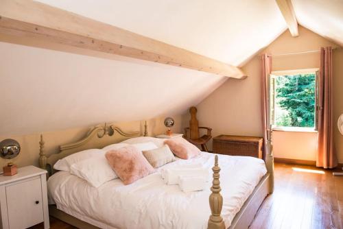 een slaapkamer met een bed met witte lakens en roze kussens bij Beautiful Home with Large Gardens and Heated Pool in Sauveterre-la-Lémance