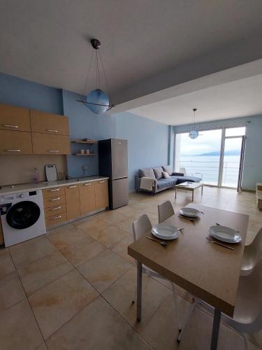 a kitchen and living room with a table and chairs at Summer Breeze Apartment Saranda in Sarandë