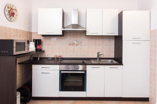 uma cozinha com armários brancos, um lavatório e um micro-ondas em Nila's Place em Dubrovnik