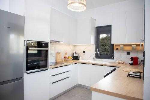 a white kitchen with white cabinets and a window at Ammira Mare Apartment in Agia Pelagia