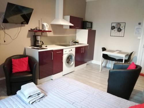 - une cuisine avec un lave-linge au milieu d'une pièce dans l'établissement Joli studio dans un ancien hôtel du XIX siècle - Proche toutes commodités - Thermes et Parc, à Vittel