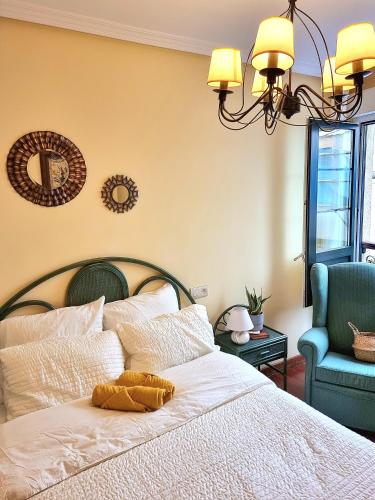a bedroom with a bed with a chandelier and a chair at a 2 min de la Catedral in Oviedo