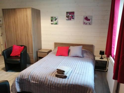 a bedroom with a bed with red and white pillows at Joli studio dans un ancien hôtel du XIX siècle - Proche toutes commodités - Thermes et Parc in Vittel