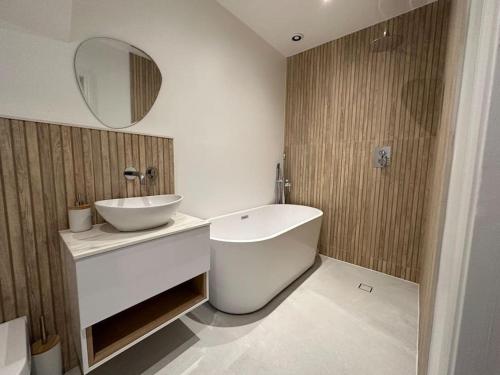 a bathroom with a tub and a sink and a mirror at Brand New Luxury 2 Bedroom House in Parkstone
