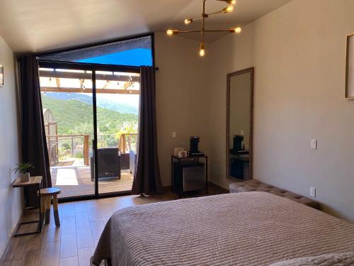 a bedroom with a bed and a large sliding glass door at Coquenas del Valle in Valle de Guadalupe