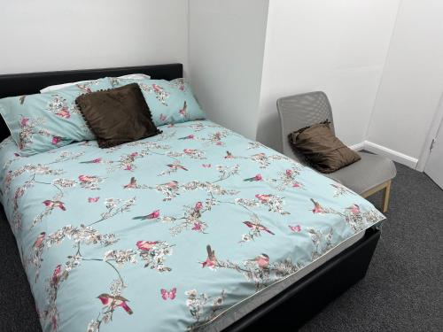HanwellにあるThe Grande Residence - Close to Central London & Next to Northfield Tube stationのベッド1台(青い掛け布団、椅子付)