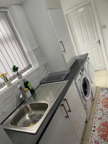 a kitchen with a sink and a washing machine at Luxury Spacious 2 Bedroom Home. in Liverpool