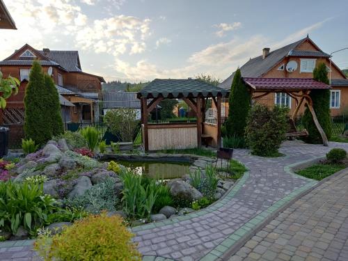 a garden with a pond in front of a house at Апартаменти "У Кузьмича" 1 in Mykulychyn