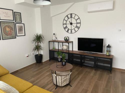 a living room with a television and a clock on the wall at Las Casas de Lola in Candeleda