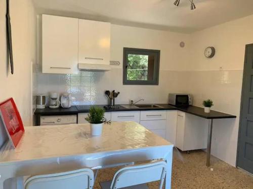 une cuisine avec des armoires blanches et une table avec des chaises dans l'établissement Beau T2 entre Santa Giulia et Palombaggia -, à Porto-Vecchio