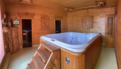 ein großes Holzbadezimmer mit einer großen Badewanne in der Unterkunft Ferienhaus 'Carolina' mit whirlpool, sauna und Grillplatz in Kossiw
