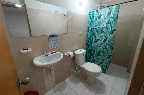 een badkamer met een toilet, een wastafel en een spiegel bij Hotel Gold Fénix in Tunja