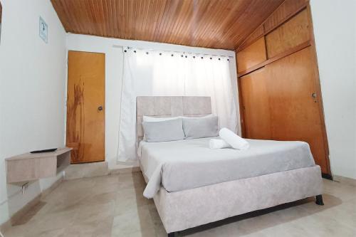 a bedroom with a large white bed with a wooden ceiling at Hotel Gold Fénix in Tunja