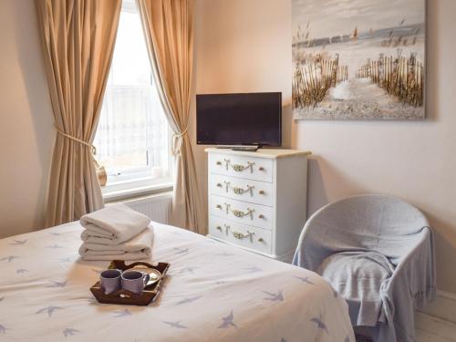 1 dormitorio con 1 cama con silla y TV en Dune-cottage en Caister-on-Sea