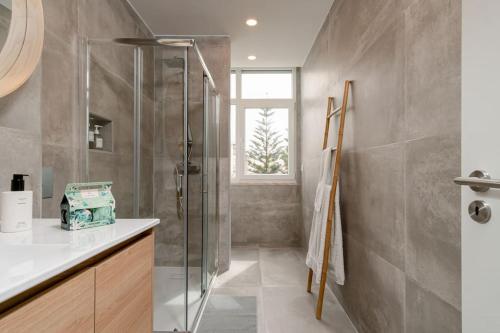 uma casa de banho com uma cabina de duche em vidro e um lavatório. em Costa Dream em Costa da Caparica