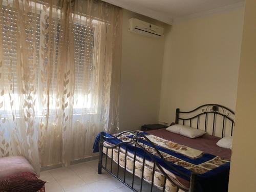 a bedroom with a bed and a window with curtains at Zagha house in Amman