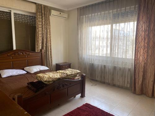 sypialnia z łóżkiem i dużym oknem w obiekcie Zagha house w mieście Amman