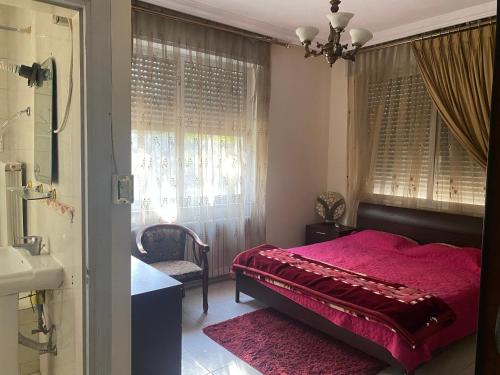 um quarto com uma cama vermelha e um lavatório em Zagha house em Amã