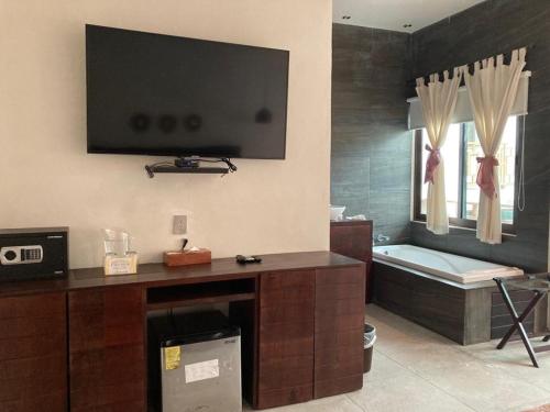 uma casa de banho com banheira e uma televisão na parede em Hotel Diosa del Agua Bacalar em Bacalar