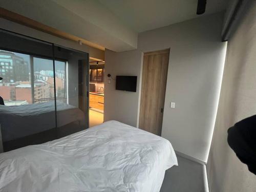 - une chambre avec un lit blanc et une porte coulissante en verre dans l'établissement Smart loft Bogota - Chico, à Bogotá