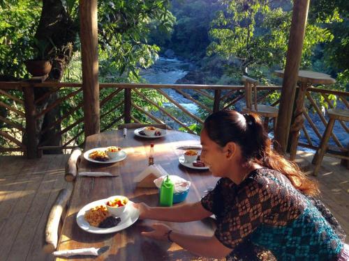 Eine Frau, die an einem Tisch mit Teller Essen sitzt. in der Unterkunft Reserva Natural Cañón Seacacar in Izabal